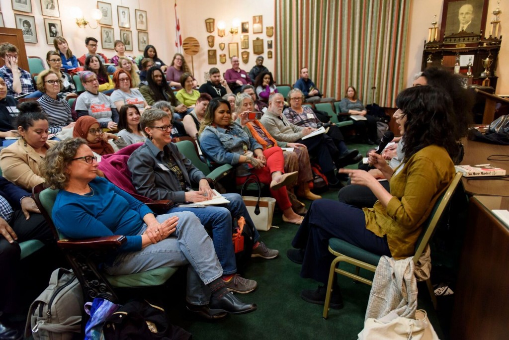 Image of a session at the 2018 festival. Panelists are seated facing a packed audience.