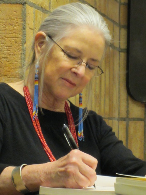 Photo of Linda Hogan wearing long blue earrings, a red necklace, and black shirt