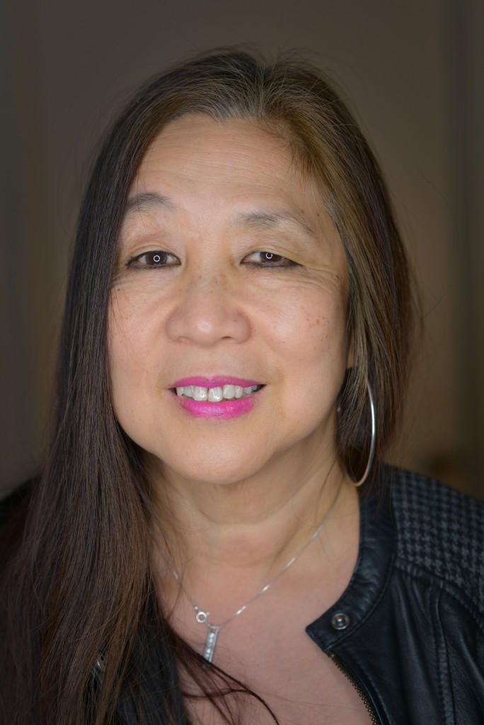 Marilyn Chin facing the camera wearing pink lipstick and a necklace.
