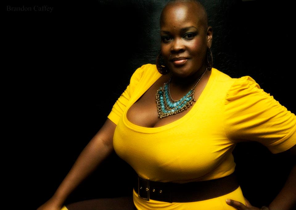 Image of Sonya Renee Taylor facing forward, wearing yellow short sleeved shirt with tourquoise necklace